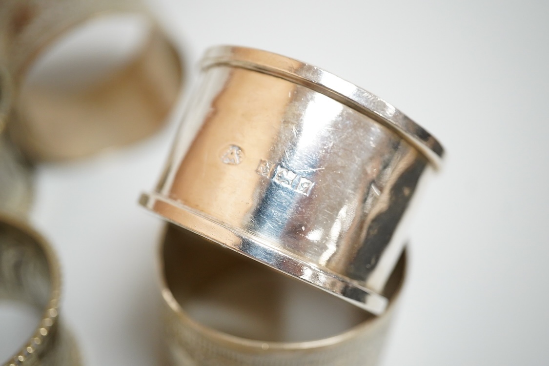 A modern silver mounted wine coaster, diameter 12cm, four silver napkin rings, four continental white metal napkin rings, a modern silver candle extinguisher, a silver tea strainer, small 925 shell dish, a George III sil